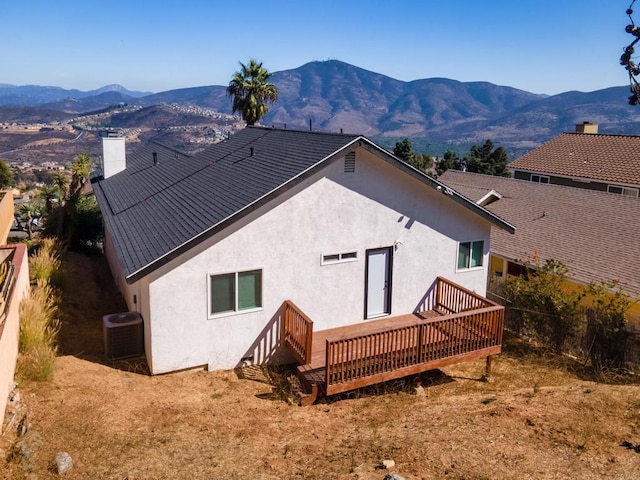 back of property featuring a chimney, stucco siding, a deck with mountain view, and central air condition unit