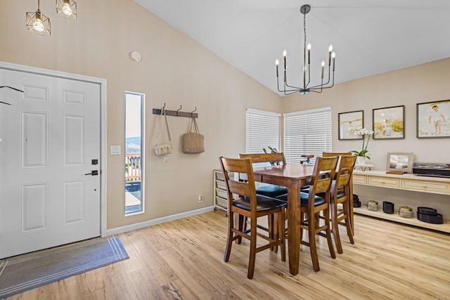 dining area with a wealth of natural light, baseboards, light wood finished floors, and an inviting chandelier