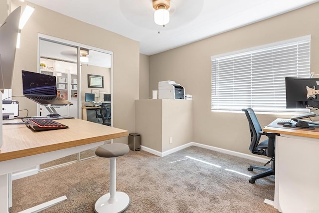 carpeted home office with baseboards and a ceiling fan