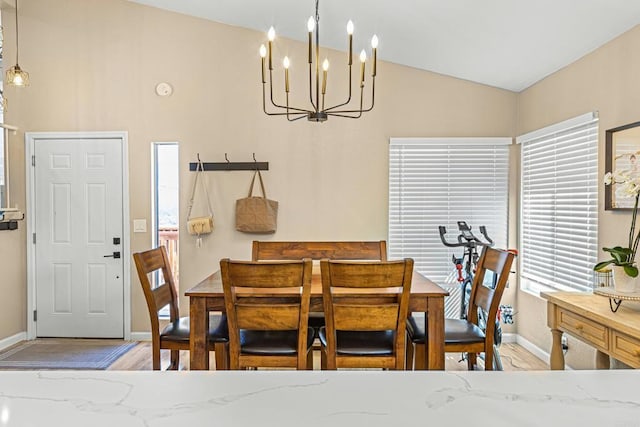 dining area with lofted ceiling, wood finished floors, a wealth of natural light, and a chandelier