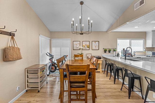 dining area featuring baseboards, vaulted ceiling, visible vents, and light wood-style floors