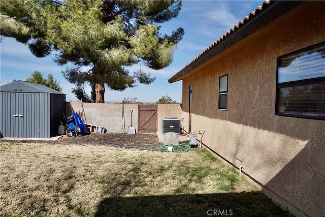 view of yard featuring a fenced backyard, a gate, an outdoor structure, central air condition unit, and a shed