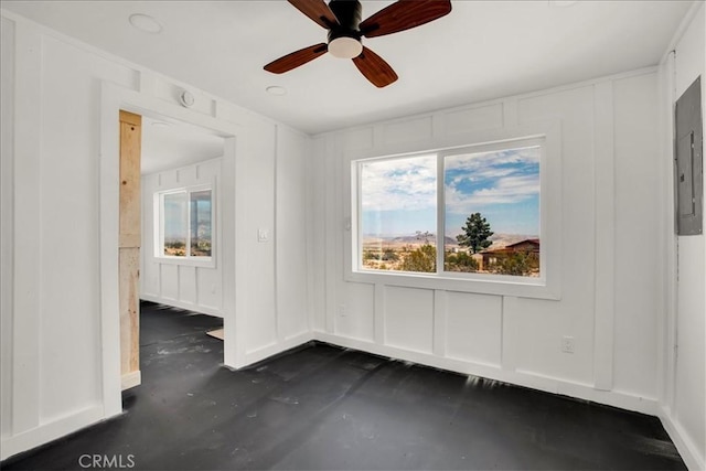 interior space with concrete flooring, electric panel, a decorative wall, and a ceiling fan