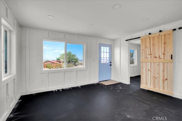 entryway featuring a barn door, concrete floors, and a decorative wall