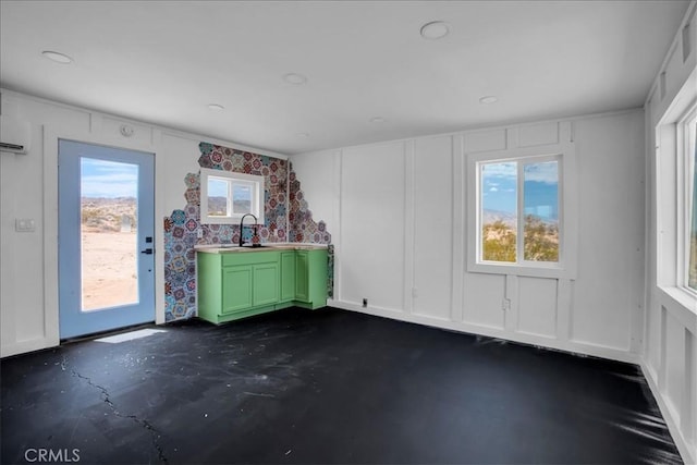 spare room featuring concrete floors, a sink, and a decorative wall