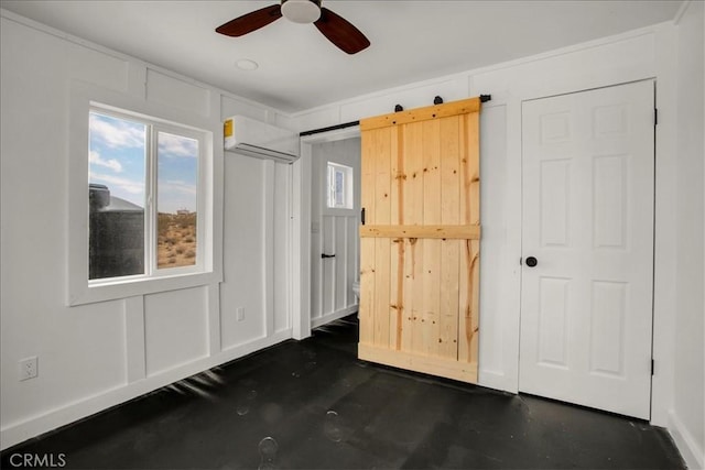 unfurnished bedroom with a barn door, a decorative wall, a ceiling fan, and a wall mounted AC