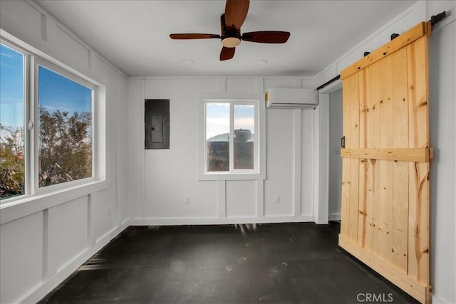 interior space featuring a wall unit AC, a decorative wall, a barn door, a ceiling fan, and electric panel