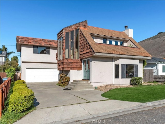 view of front of house featuring concrete driveway, stucco siding, an attached garage, fence, and a front yard