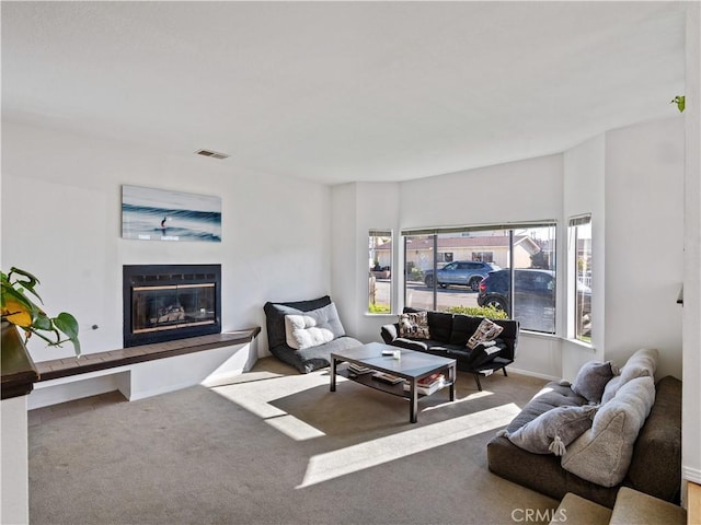 living room with carpet floors, a glass covered fireplace, visible vents, and baseboards