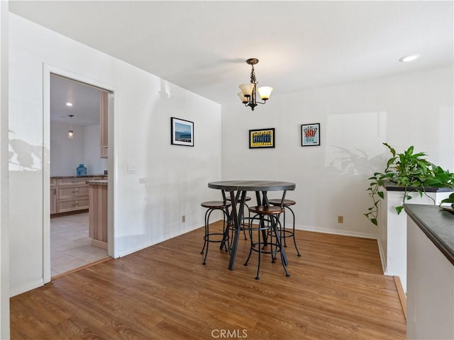 dining space with light wood-style flooring, baseboards, a notable chandelier, and recessed lighting