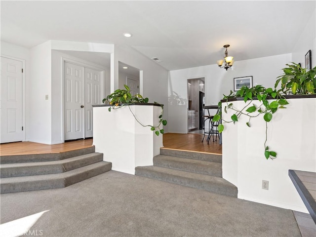 carpeted foyer featuring stairway, recessed lighting, visible vents, and a notable chandelier