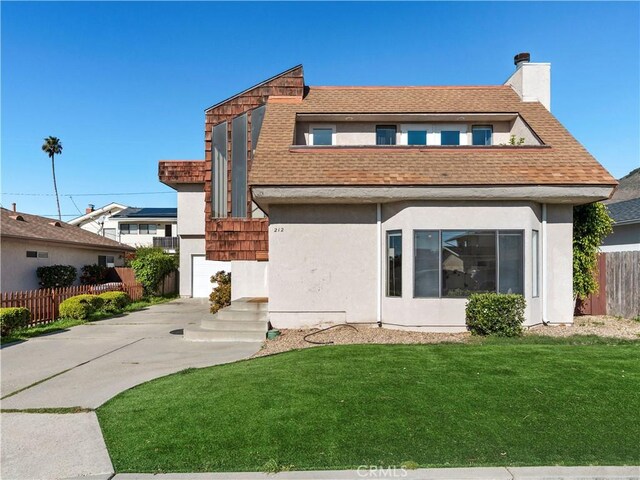 rear view of property with a chimney, stucco siding, a shingled roof, a lawn, and fence