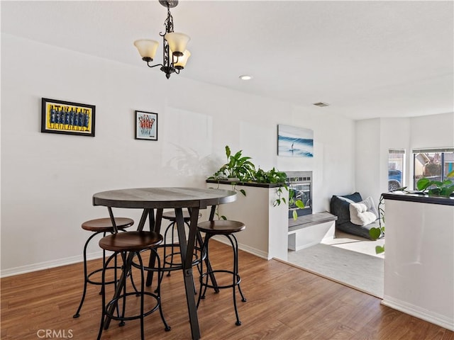 dining space featuring a notable chandelier, baseboards, visible vents, and wood finished floors