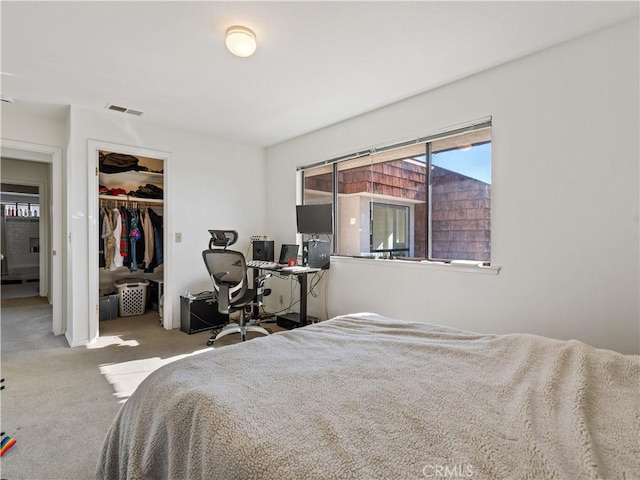 bedroom with light colored carpet, a closet, visible vents, and a spacious closet