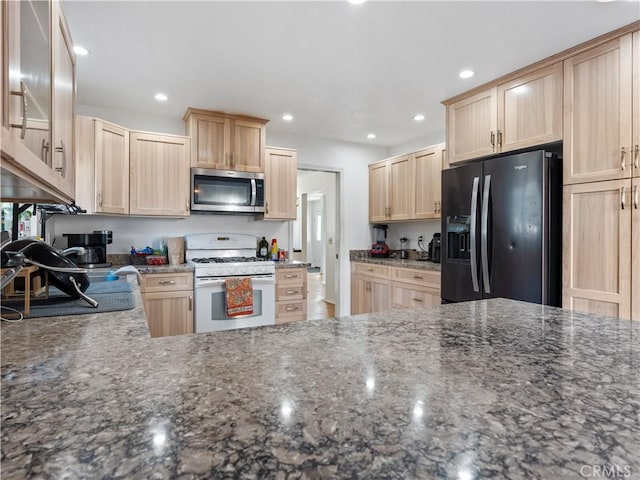 kitchen featuring stainless steel microwave, refrigerator with ice dispenser, light brown cabinets, and white gas range oven