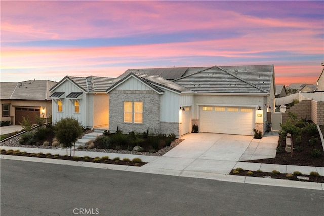 view of front of property with a garage, board and batten siding, solar panels, and concrete driveway