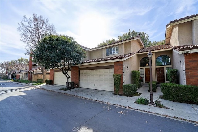 view of front facade featuring a garage, a tile roof, driveway, and stucco siding