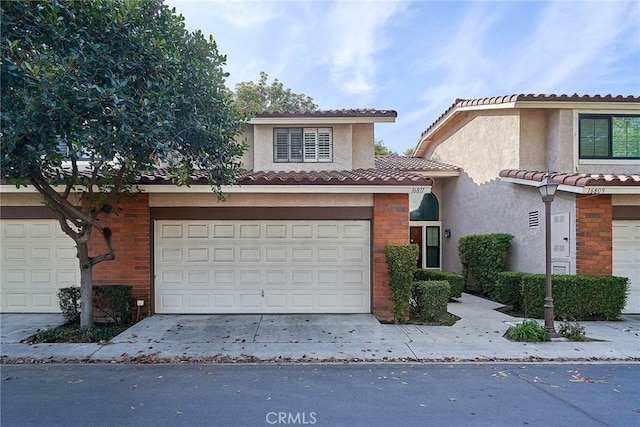 view of front of house with brick siding, stucco siding, a garage, driveway, and a tiled roof