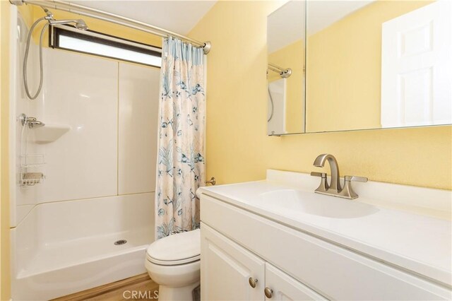 bathroom featuring a shower stall, toilet, and vanity