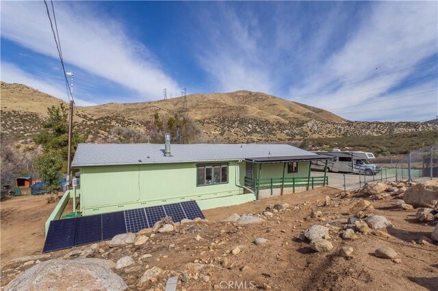 rear view of house featuring a mountain view and solar panels