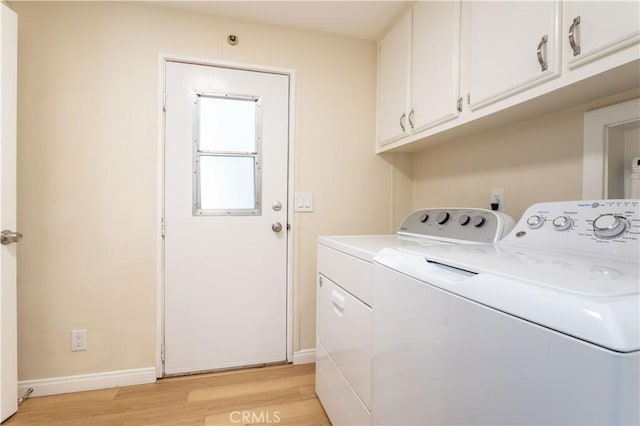 laundry area featuring light wood-type flooring, washer and dryer, cabinet space, and baseboards