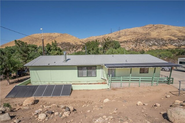 rear view of house with solar panels and a mountain view