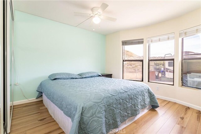 bedroom with a ceiling fan, baseboards, and light wood finished floors