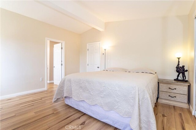 bedroom with lofted ceiling with beams, light wood finished floors, and baseboards