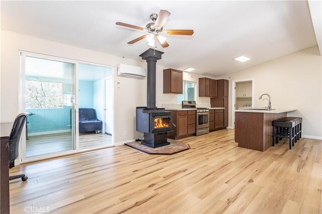 kitchen with light countertops, an AC wall unit, stainless steel range oven, a wood stove, and a peninsula