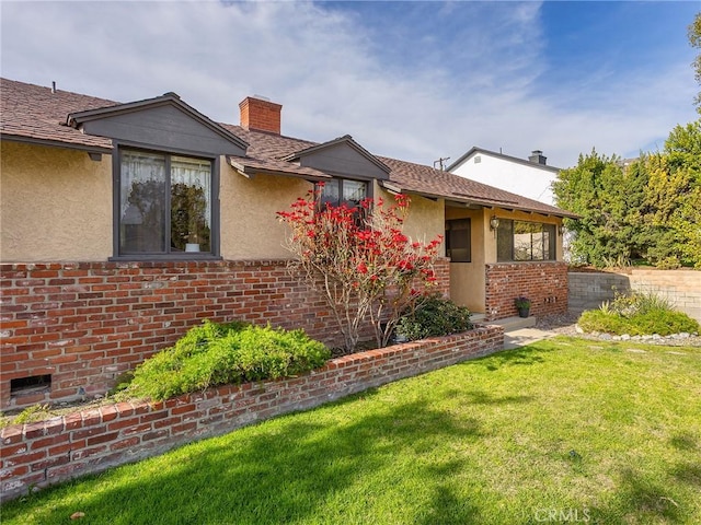 ranch-style home with brick siding, a chimney, and a front yard