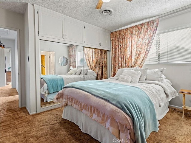 bedroom with a textured ceiling, carpet floors, multiple windows, and visible vents