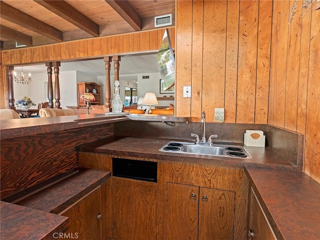 kitchen with beam ceiling, dark countertops, visible vents, wood ceiling, and a sink