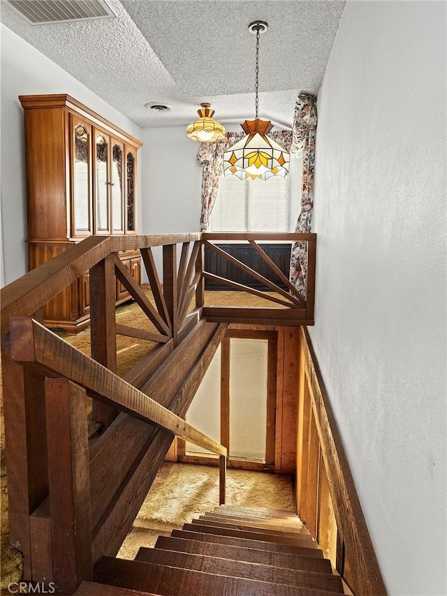 staircase with a textured ceiling and visible vents