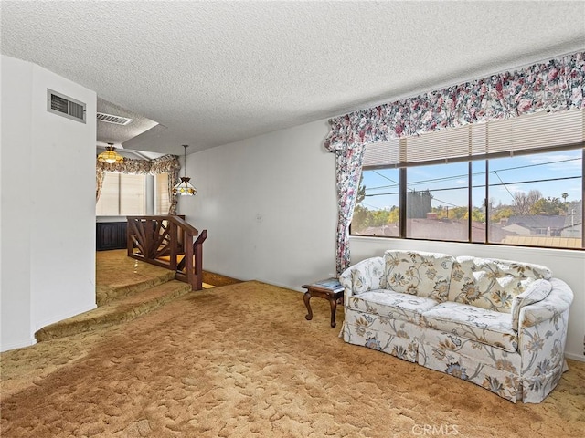 carpeted living room with a textured ceiling, visible vents, and a ceiling fan