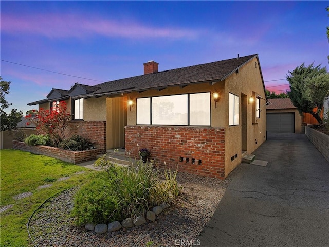 view of front of home with brick siding, a chimney, crawl space, an outdoor structure, and stucco siding