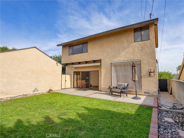 back of house featuring a patio area, fence, a lawn, and stucco siding