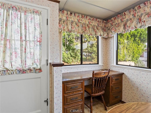 office area with built in study area and wallpapered walls