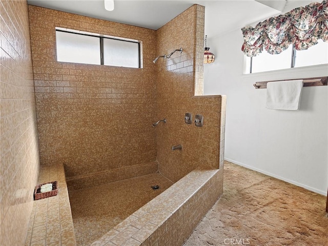 full bathroom featuring tiled shower and baseboards