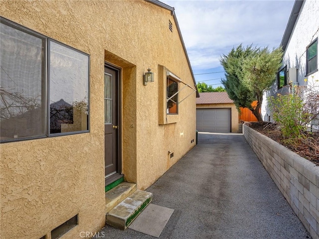 view of home's exterior with a garage, an outdoor structure, and stucco siding