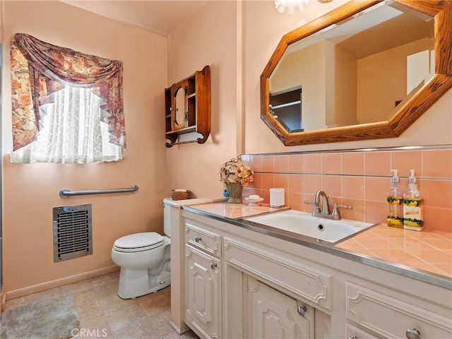 bathroom featuring heating unit, toilet, vanity, backsplash, and tile patterned floors