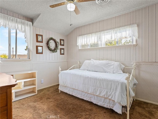 bedroom featuring a textured ceiling, multiple windows, dark carpet, and wallpapered walls