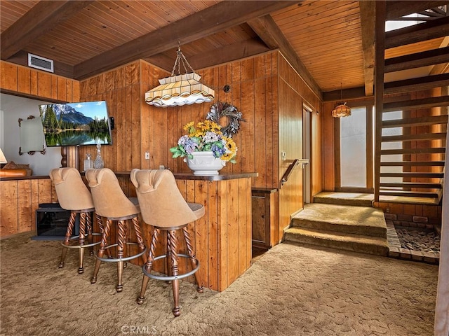 interior space with wood walls, carpet, visible vents, and decorative light fixtures