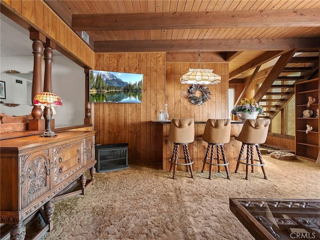 interior space featuring wood ceiling, beamed ceiling, hanging light fixtures, carpet flooring, and wood walls