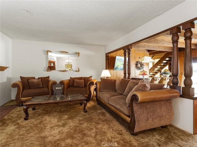 carpeted living room with decorative columns, a textured ceiling, and stairs