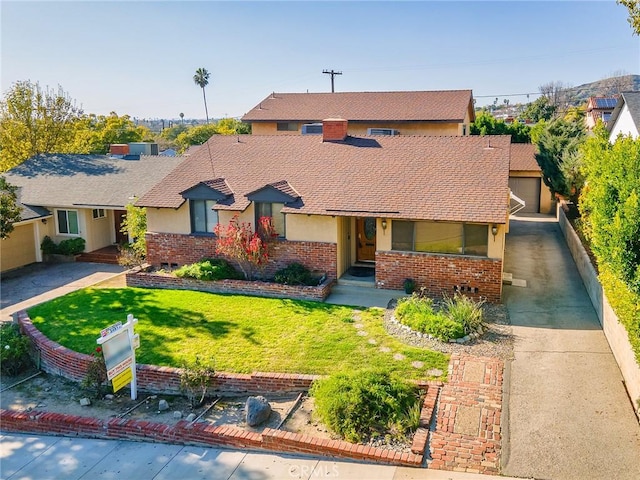 traditional-style house with a shingled roof, brick siding, driveway, and a front lawn