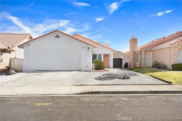 view of front of home featuring stucco siding, concrete driveway, an attached garage, fence, and a residential view