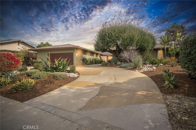 view of front of property featuring concrete driveway, an attached garage, and stucco siding