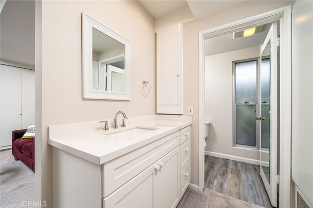 bathroom featuring connected bathroom, wood finished floors, visible vents, vanity, and baseboards