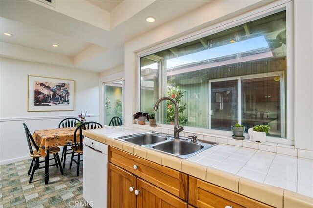 kitchen featuring tile countertops, white dishwasher, a sink, and recessed lighting