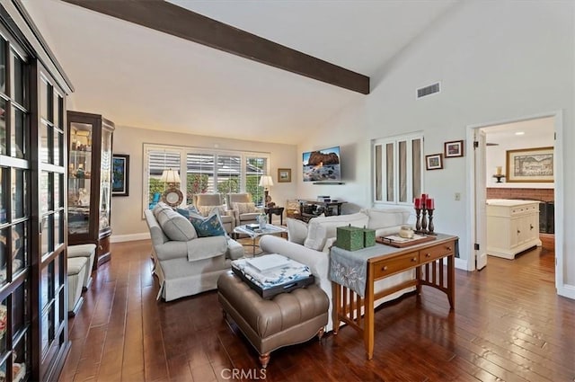 living area featuring hardwood / wood-style floors, beamed ceiling, visible vents, and baseboards